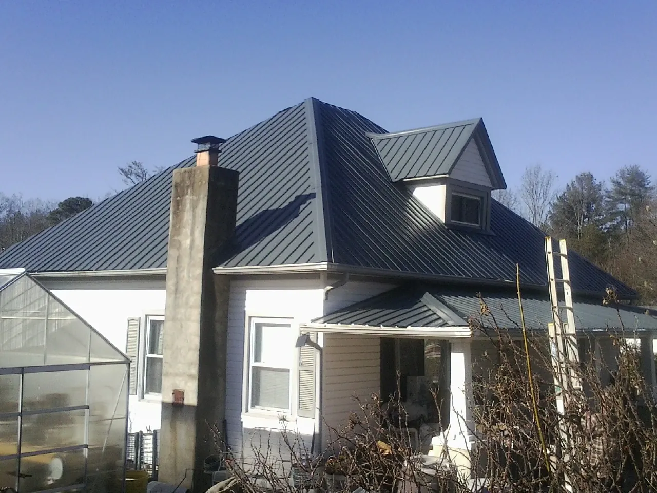 Dark blue standing seam metal roof on a white farmhouse with dormer — Slate & Tile Roof Repair by Roofing Brothers in Monroe